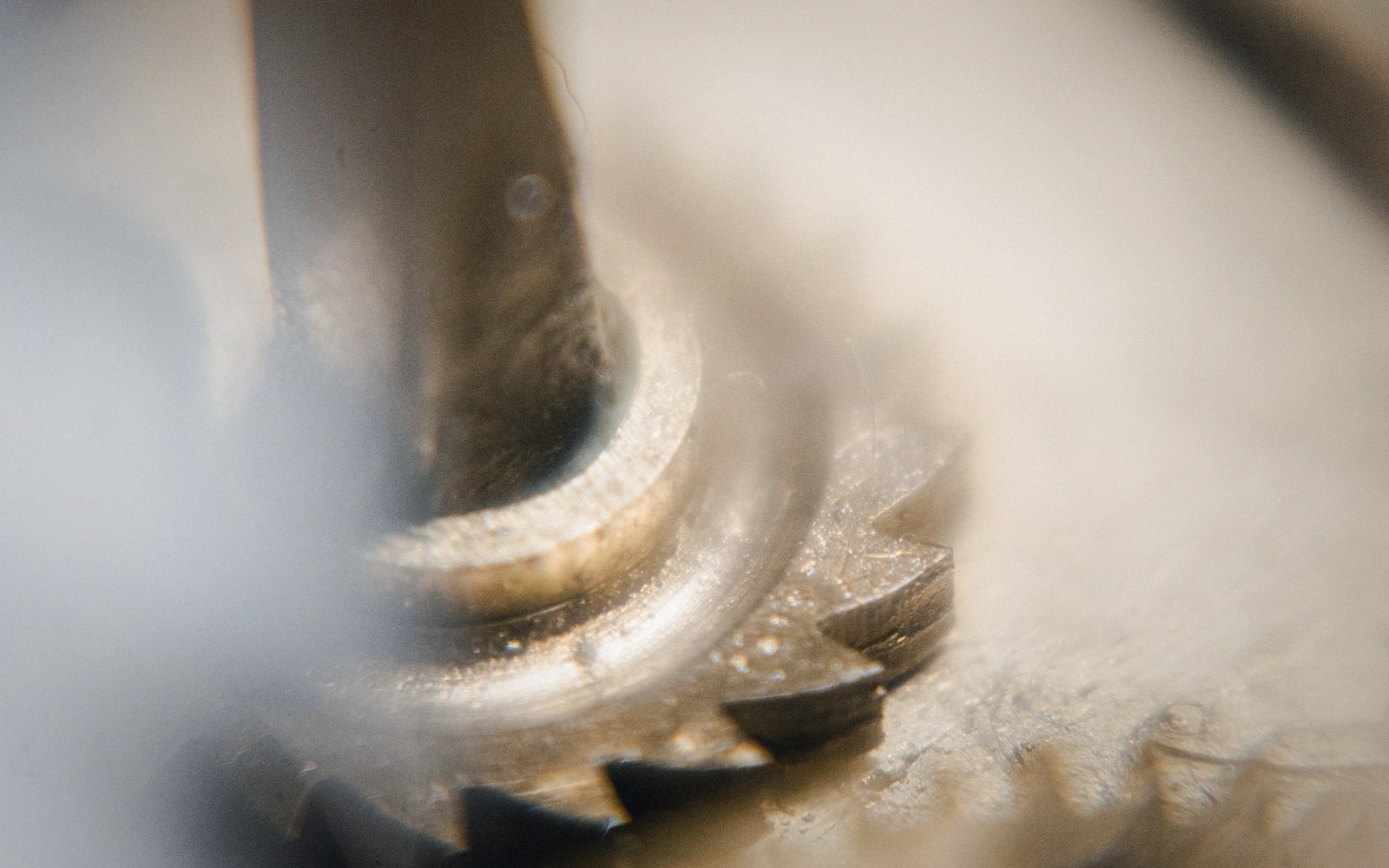 Extreme close-up of a metal gear's teeth meshing with a threaded shaft component