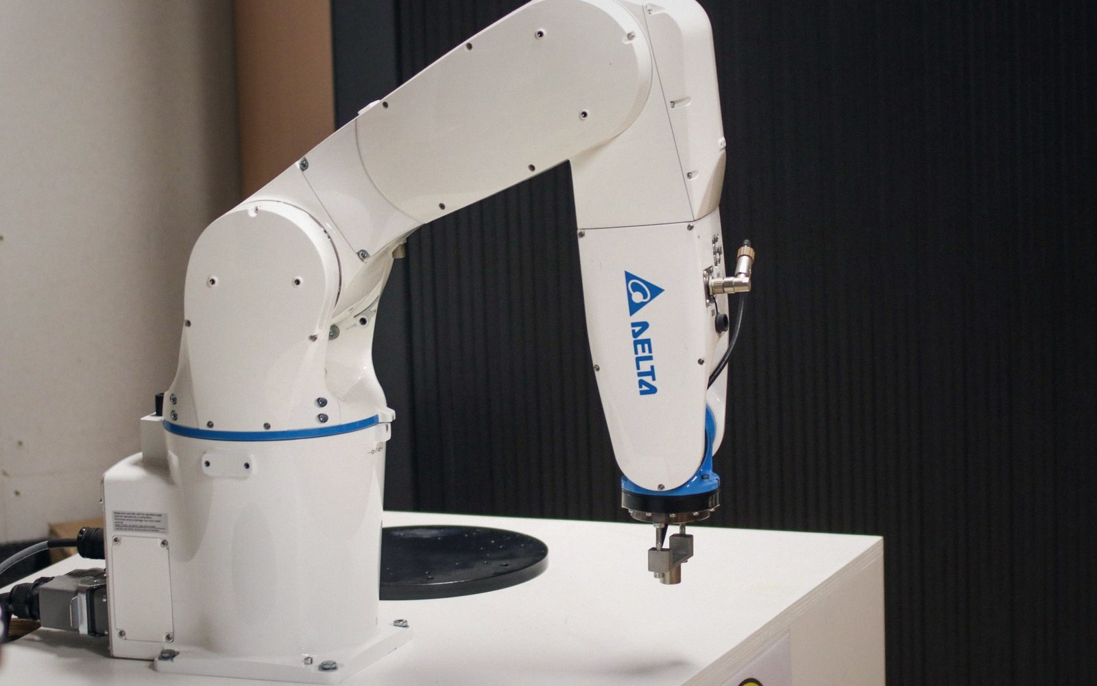 A white Delta robotic arm with a tool tip positioned above a work surface