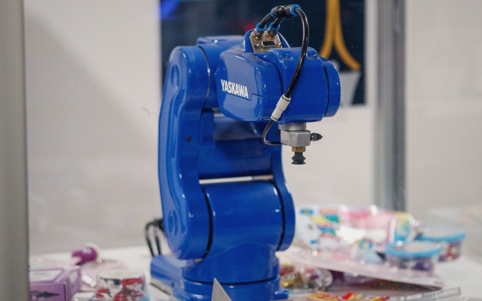 A blue Yaskawa robotic arm on display next to small packaged items
