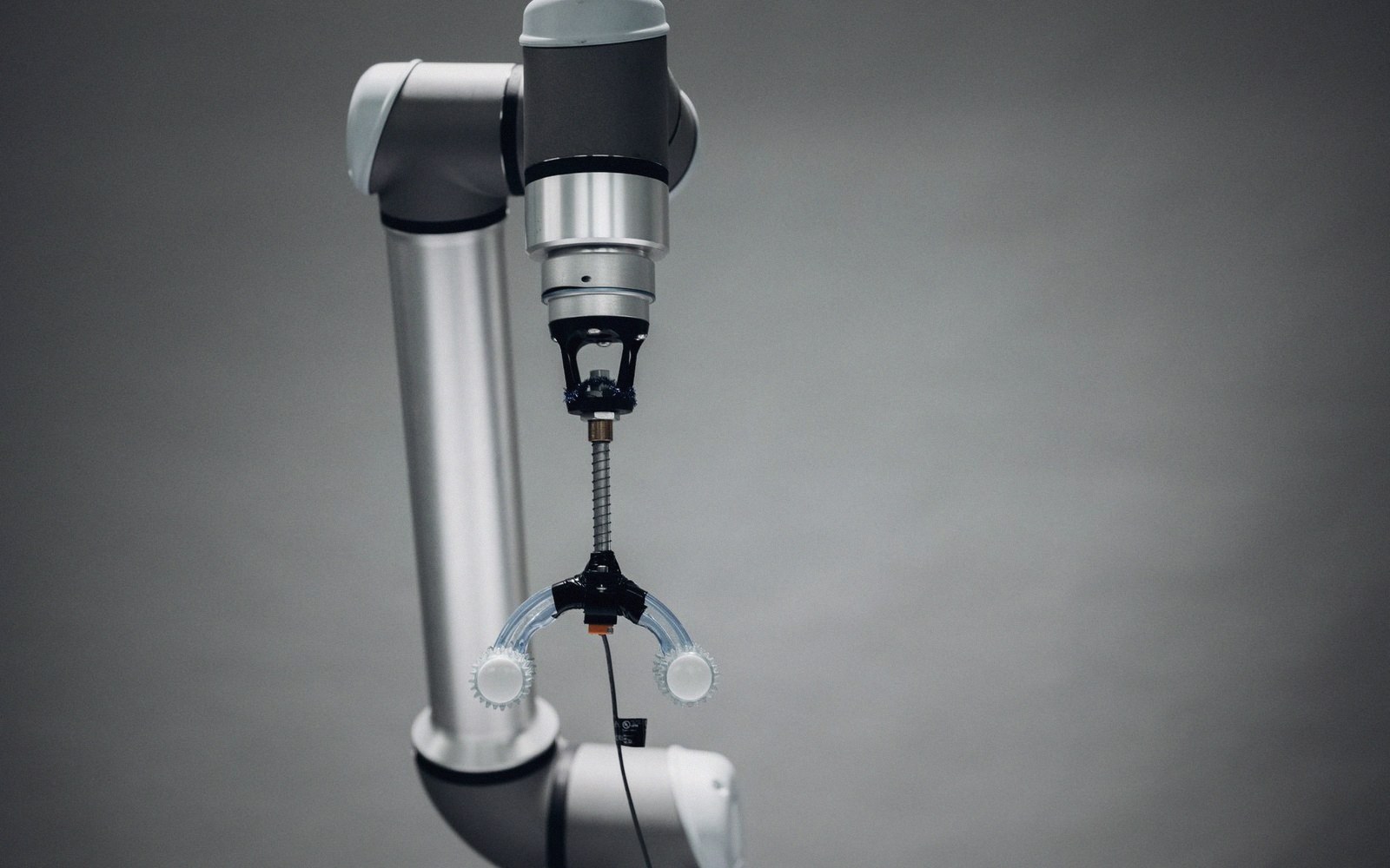 Robotic arm with a suction-cup gripper attachment against a gray background