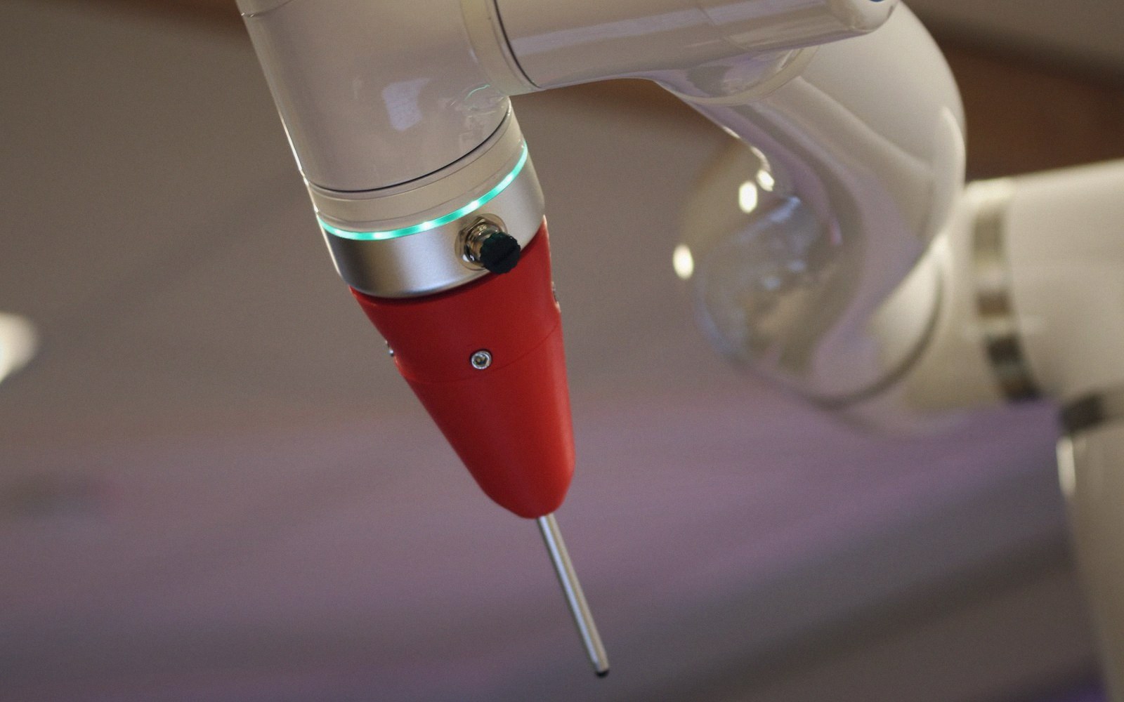 Close-up of a robotic arm's jointed segments with a red end effector and glowing green ring
